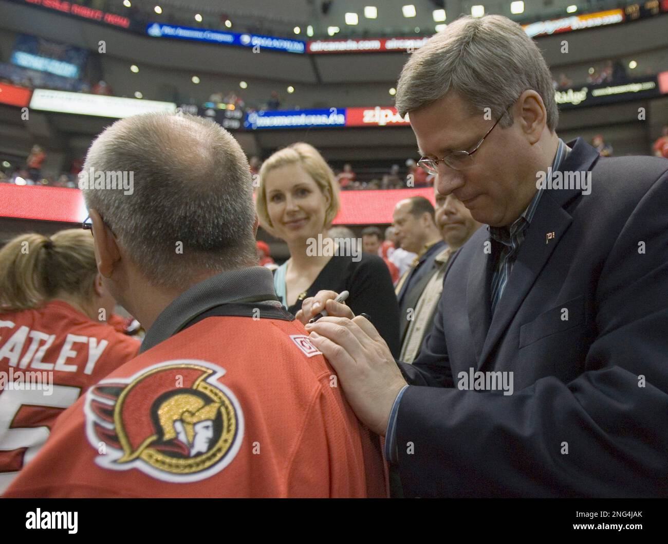Canadian Prime Minister Stephen Harper autographs a fan's jersey