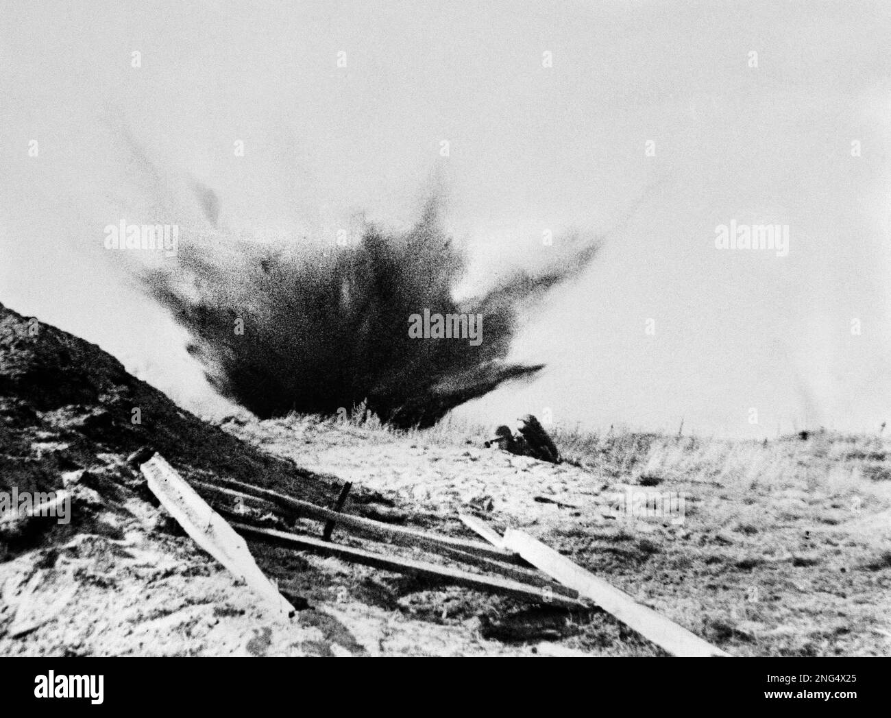 A German fire thrower, attacks a Soviet Bunker as artillery shells explode in the background
