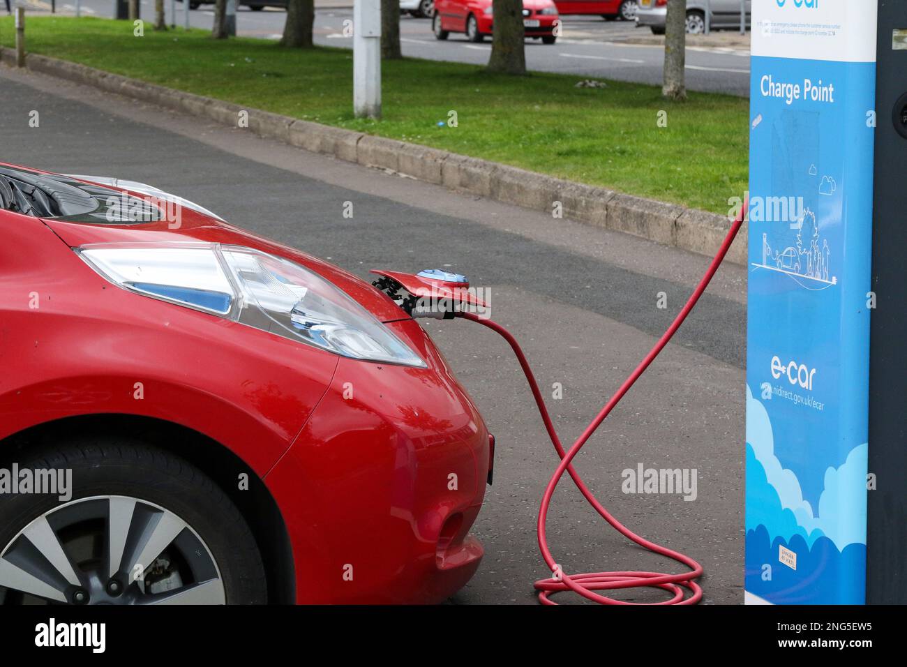 UK EV Charging bay with Red Nissan electric car with red charging cable