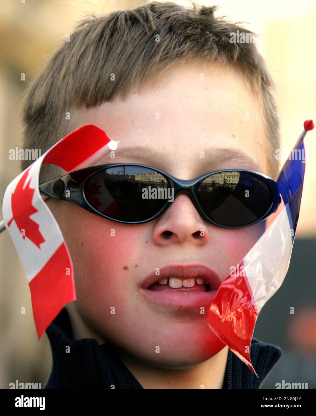 A young boy with small Canadian and French flags attached to his ...
