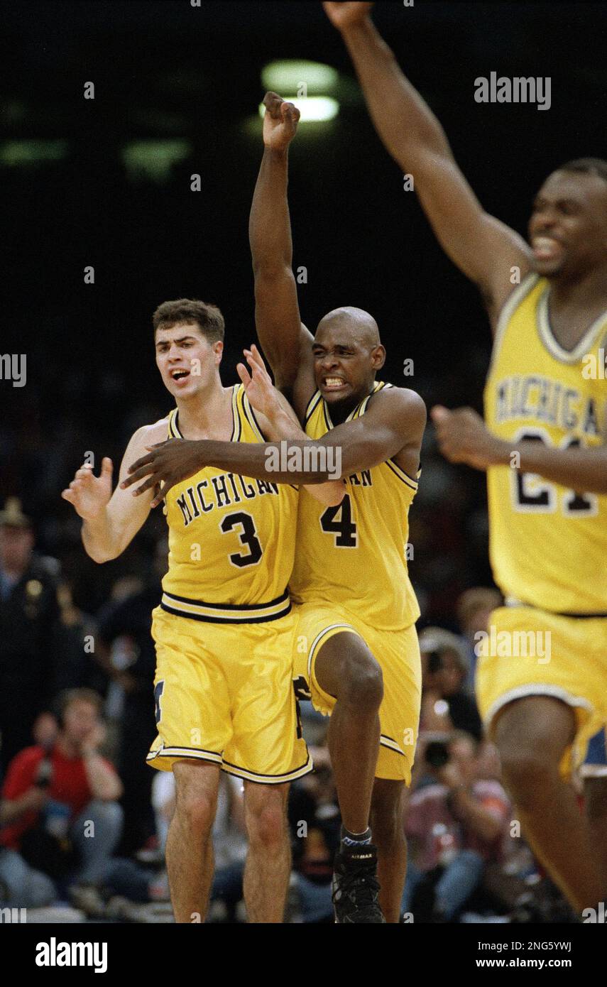 Michigan's Chris Webber (4), Rob Pelinka (3) and Ray Jackson, right,  celebrate in New Orleans as they beat Kentucky, 81-78 in overtime to  advance to Monday's final with North Carolina, April 3,