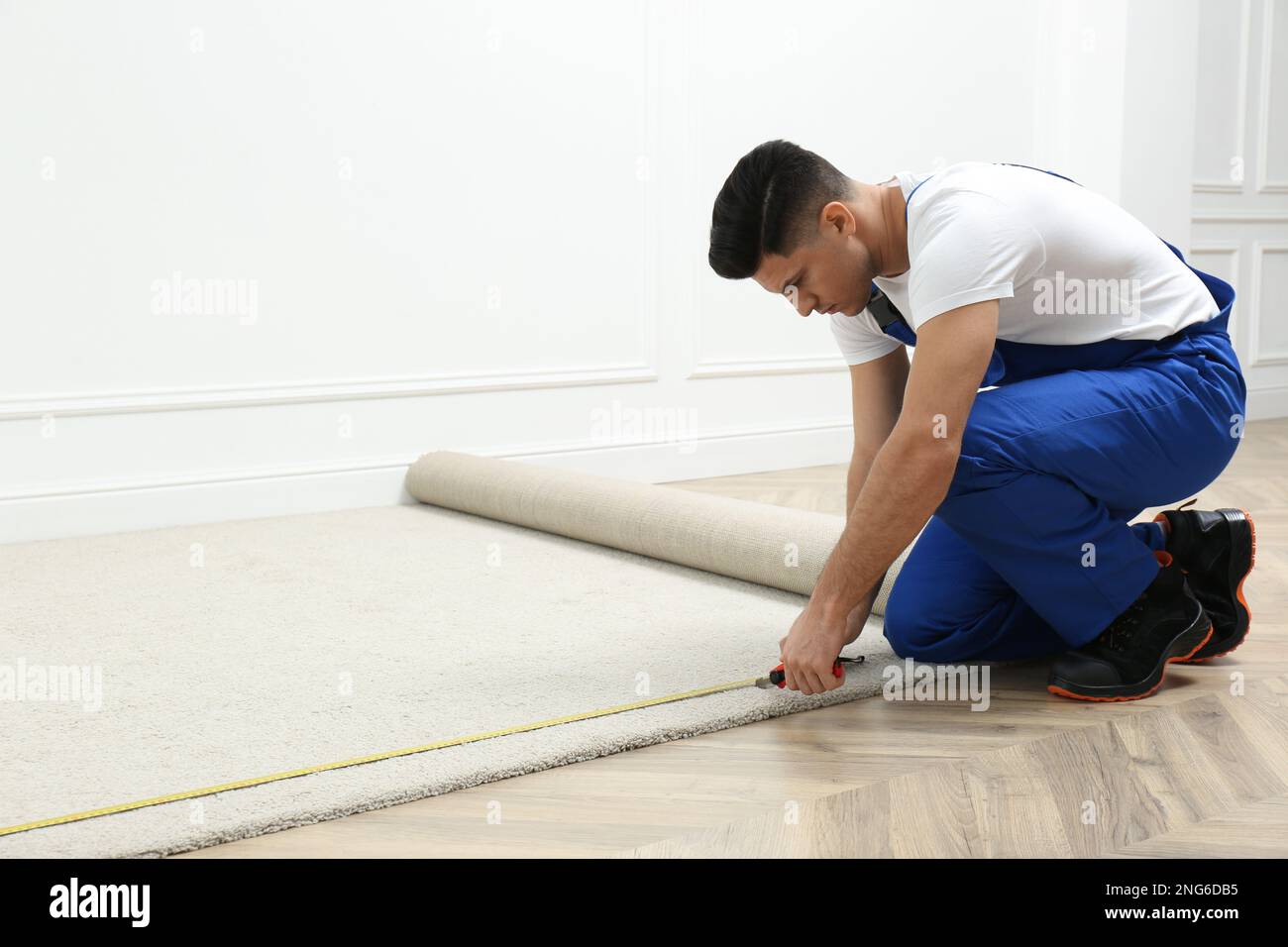 Worker with measuring tape installing new carpet indoors Stock Photo Alamy