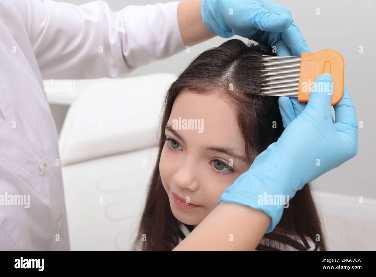 Doctor using nit comb on little girl's hair indoors. Anti lice
