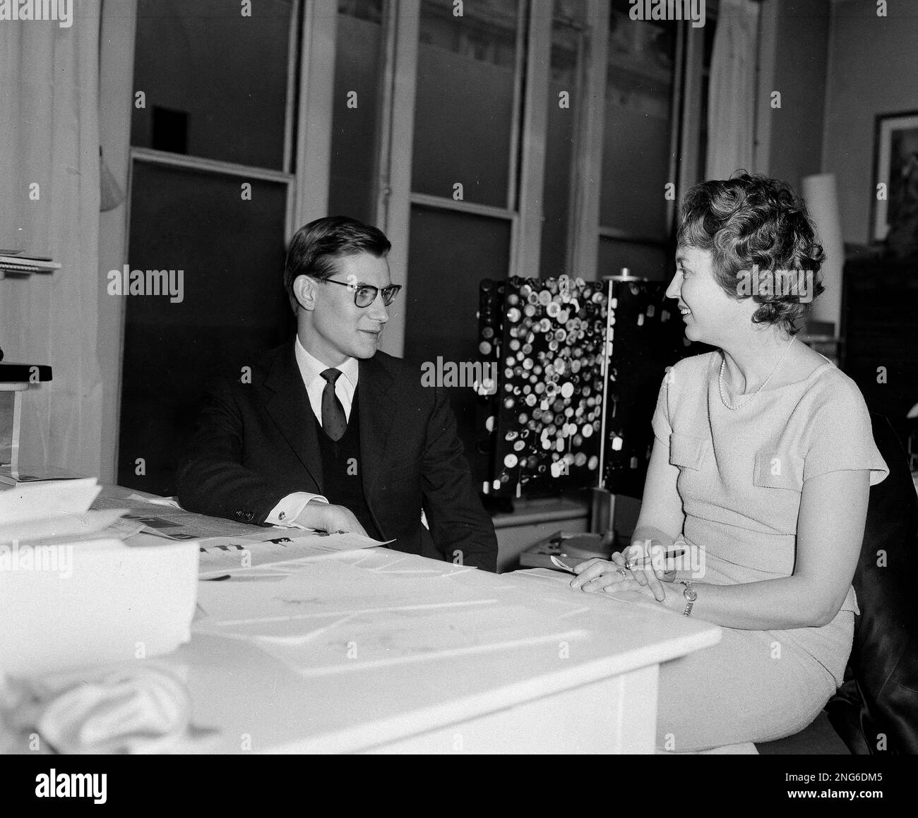 French fashion designer Yves Saint Laurent, 21-year-old successor to the  late Christian Dior, is interviewed by Nadine Walker, Associated Press  reporter, at the designer's office in Paris, March 14, 1958. Upon the