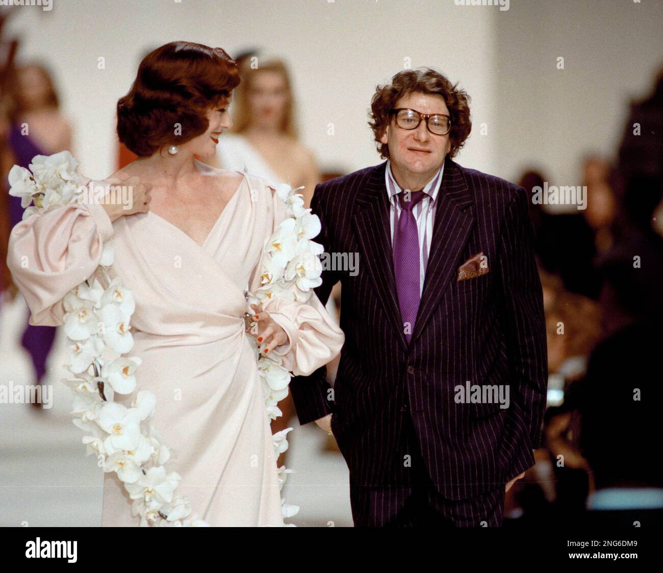 French designer Yves Saint Laurent walks with his model presenting