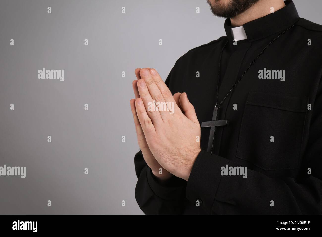 Priest praying on grey background, closeup. Space for text Stock Photo