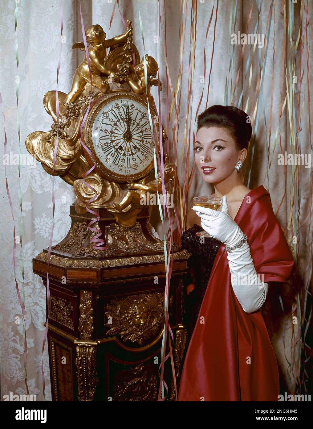 Actress Joan Collins is shown Oct. 1, 1959 holding a champagne glass next  to a clock. (AP Photo Stock Photo - Alamy