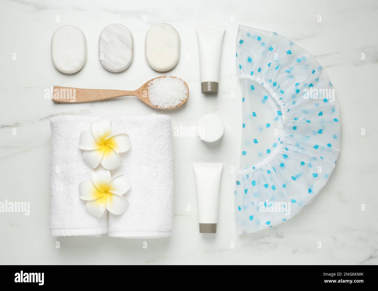 Flat lay composition with shower cap and toiletries on white marble ...
