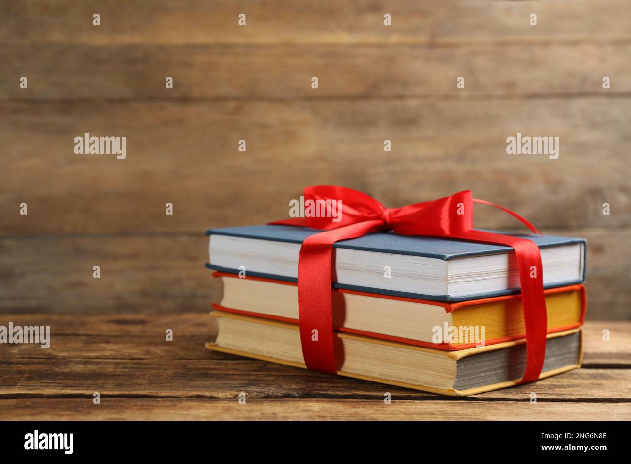 Different books tied with red ribbon on wooden table, space for text ...