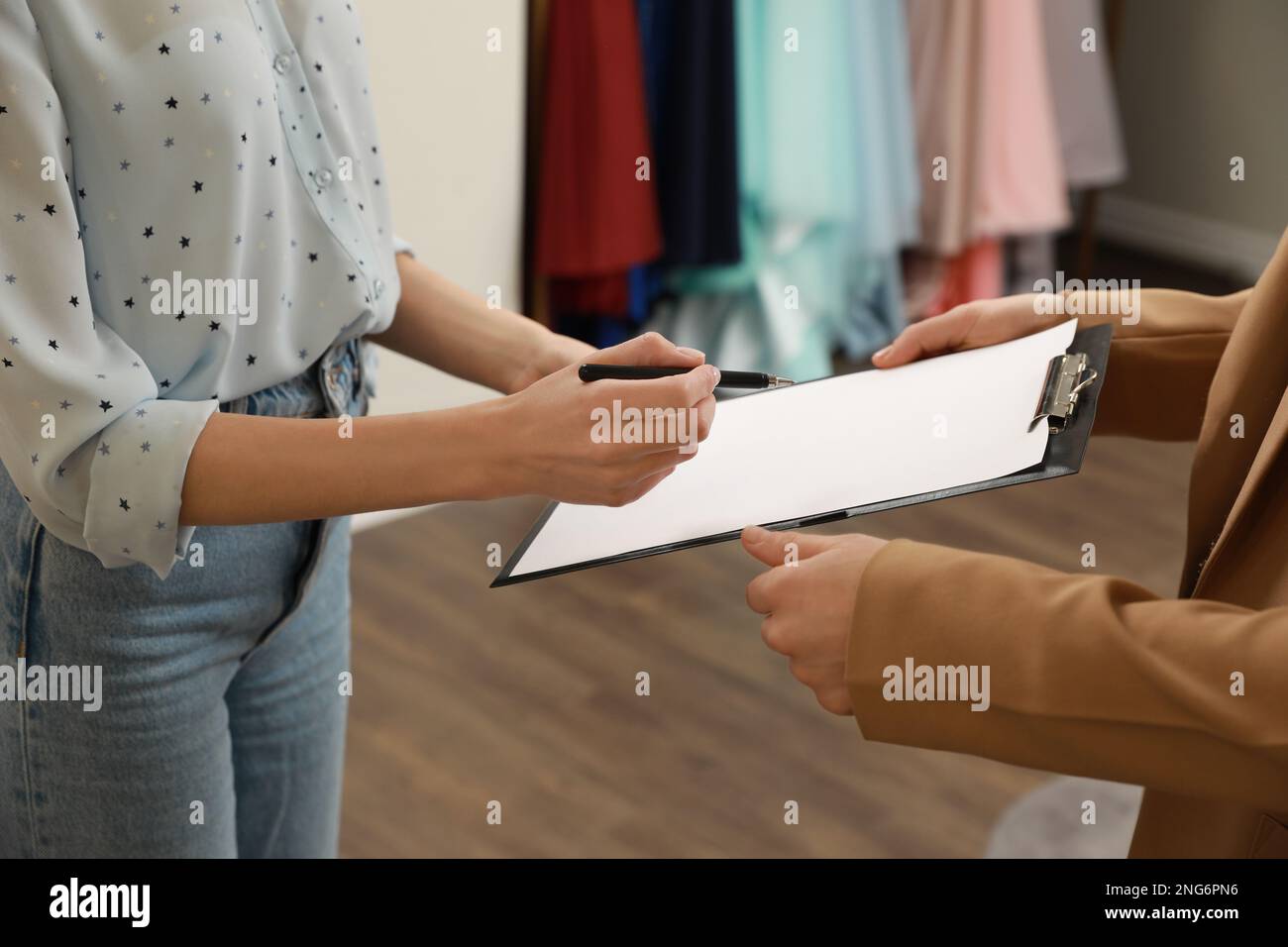 Woman signing rental agreement in clothing salon, closeup Stock Photo