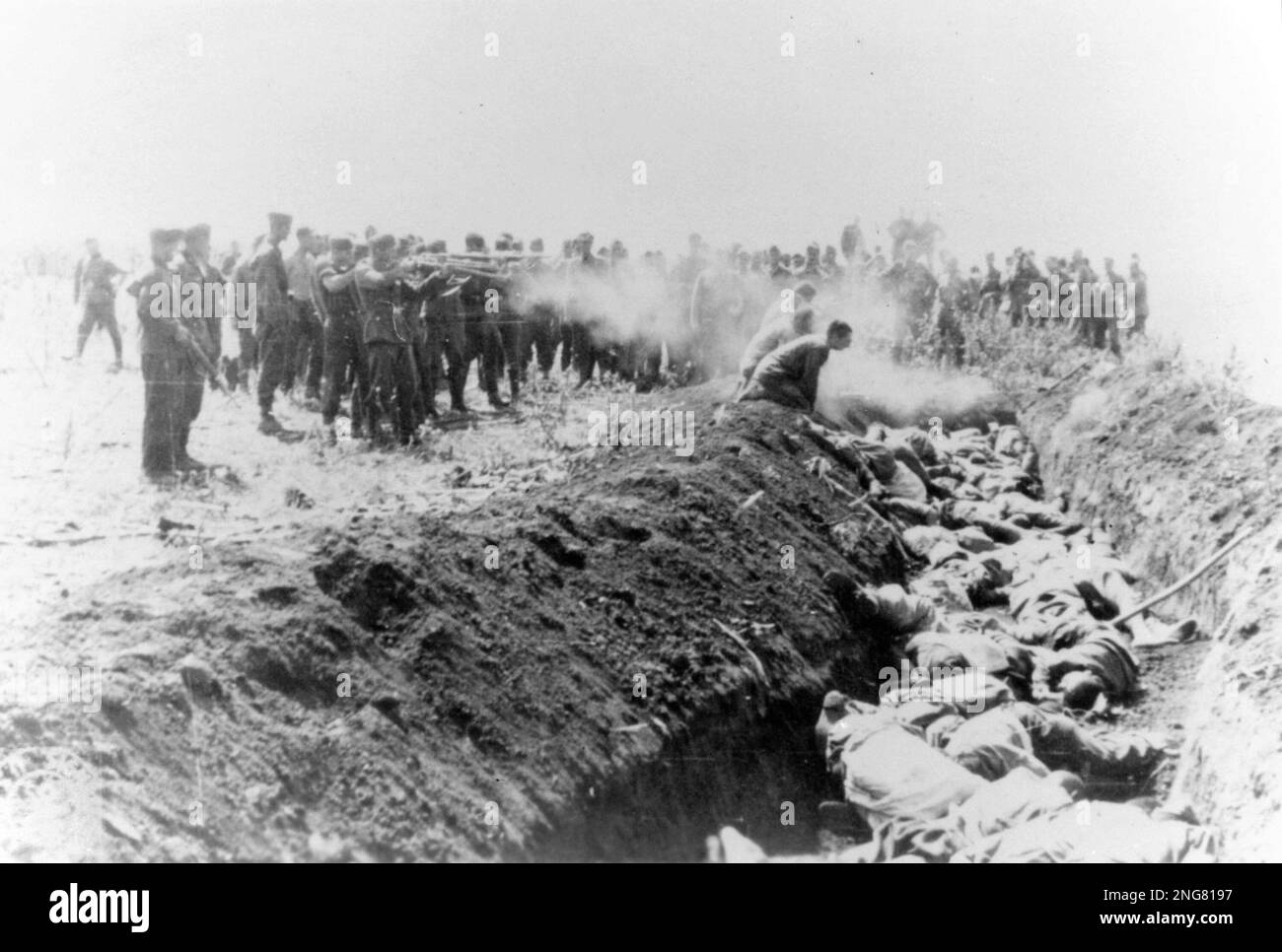The early phase of the Holocaust was not with gas chambers but mobile execution squads known as Enisatzgruppen. Their task was to roam behind teh front lines shooting all the Jews they could. They killed an estimated  two million people.  This photo shows the men firing at their victims kneeling by a ditch into which their bodies will fall. Stock Photo