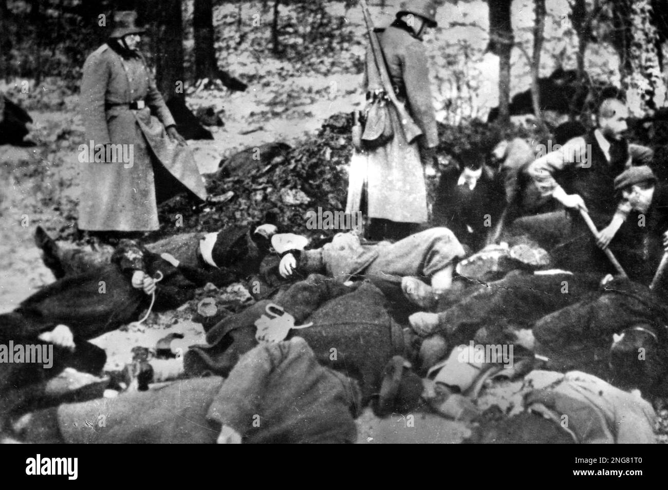 The early phase of the Holocaust was not with gas chambers but mobile execution squads known as Enisatzgruppen. Their task was to roam behind teh front lines shooting all the Jews they could. They killed an estimated  two million people.  This photo shows Germansoldiers overseeing the burial of bodies after an execution. Stock Photo