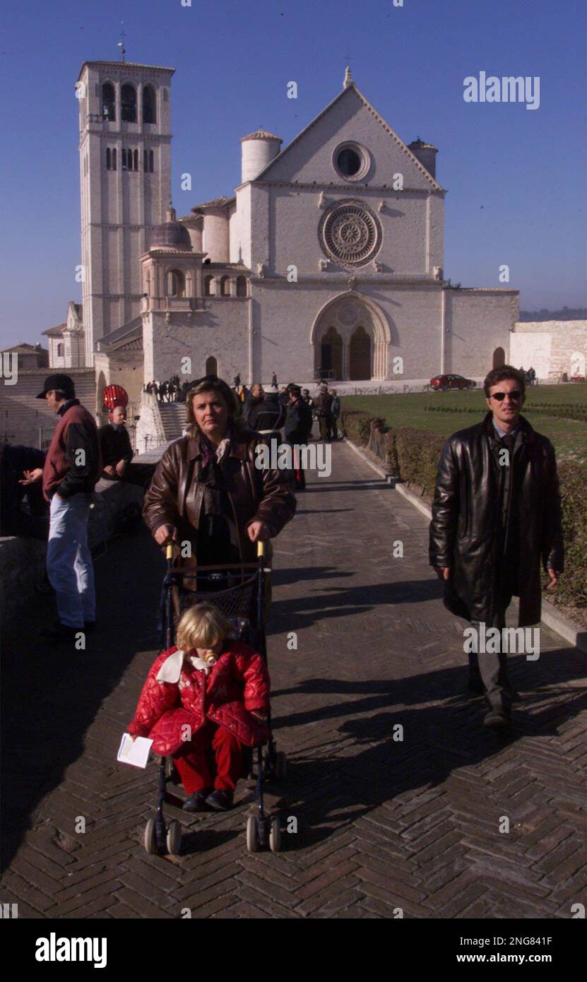 People walk on a sunny day in the area outside the Basilica of St