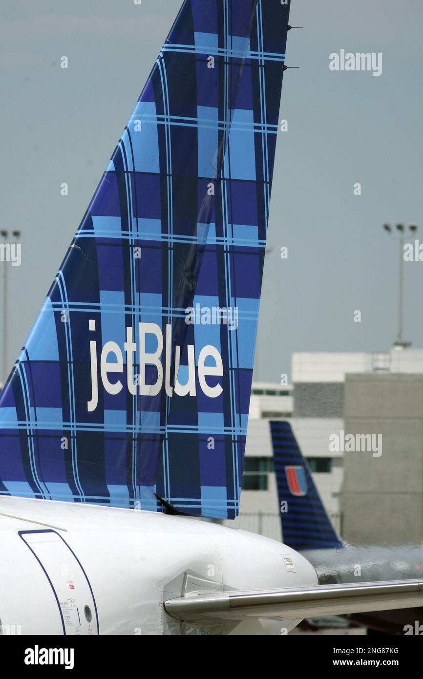 The company logo of JetBlue is shown on the tail of a plane at a gate