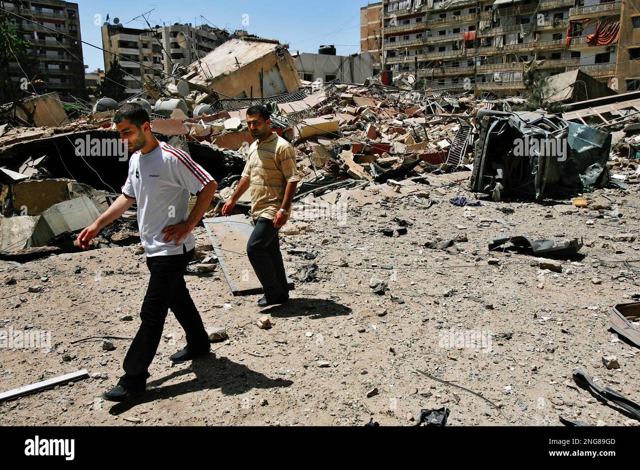 Lebanese men pass after viewing the destroyed building that used to house  the offices and studios of Hezbollah's Al-Nour radio station in the  Hezbollah stronghold suburbs of Beirut, Lebanon, Saturday, Aug. 12,