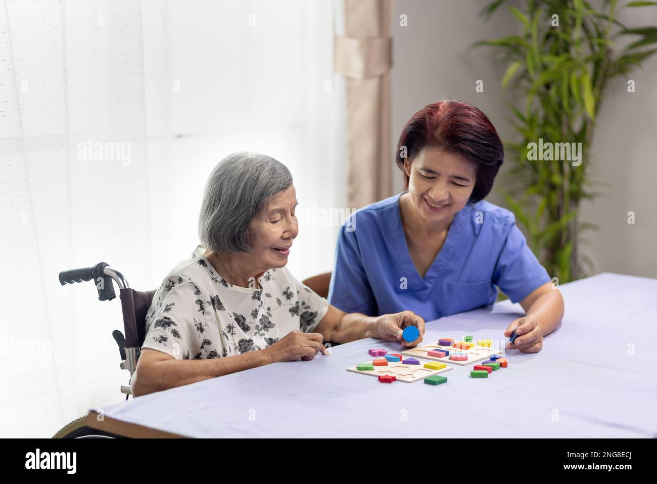 Caregiver and senior woman playing wooden shape puzzles game for