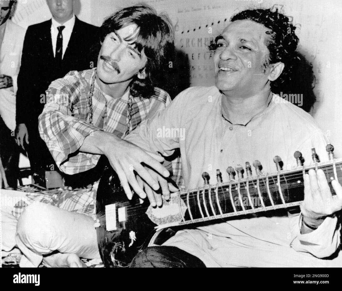 Beatle Harrison, left, sits crosslegged with musical mentor