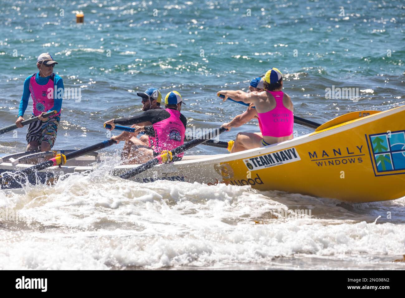 Australian male surfboat crew rowing their traditional surfboat in the