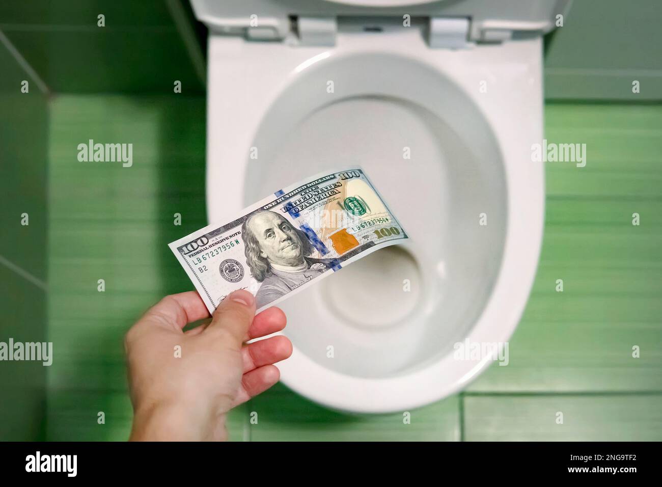 Flush money down toilet, throws dollar bills in the toilet, loss concept, close up, selective