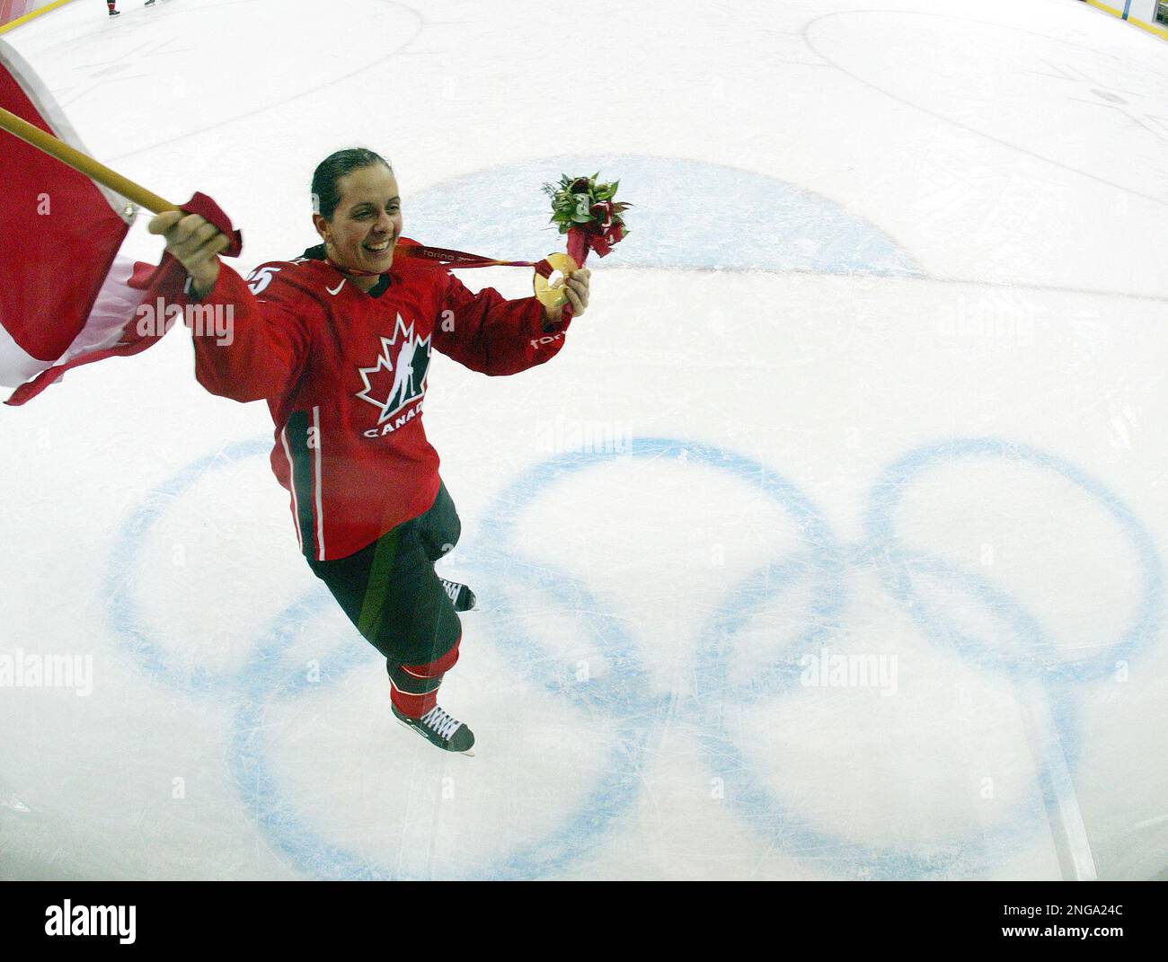 Team Canada's Danielle Goyette carries her nations flag as she shows off her gold medal after Canada defeated Sweden 4-1 in the womens ice hockey gold medal match of the 2006 Turin Winter Olympic Games in Turin, Italy Monday Feb. 20, 2006. (AP Photo/Julie Jacobson) Stock Photo