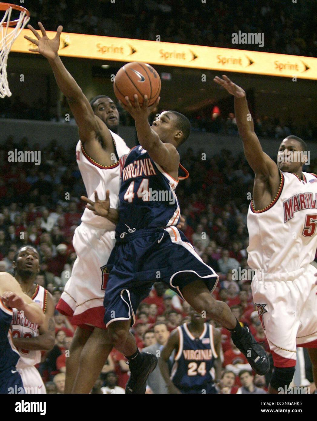 Virginia's Sean Singletary (44) drives to the basket as Maryland's Travis Garrison, left, and D