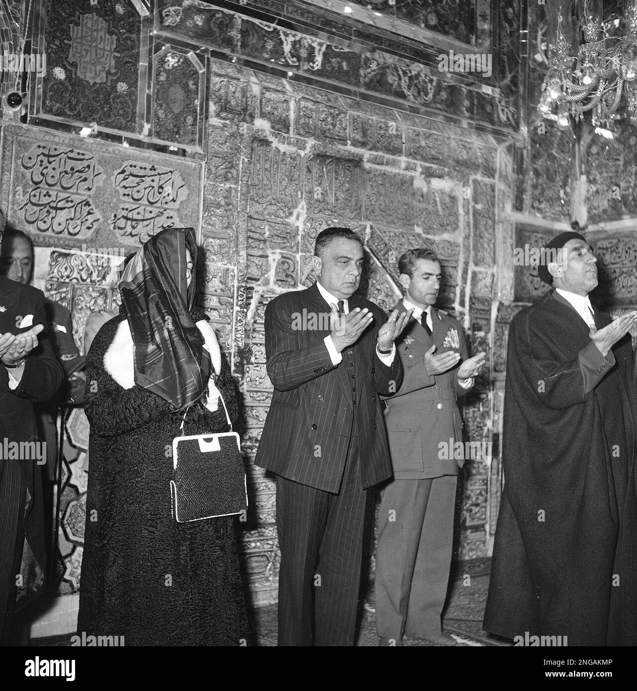 President Iskander Mirza of Pakistan, center, is seen at prayer during a state visit to Iran, at the Masshad holy shrine, at the tomb of the Imam Reza, Nov. 6, 1956. From left to right, Mirza's wife Begum Mirza; Mirza; and Shah of Iran, Reza Shah Pahlevi. Man at far right is unidentified. (AP Photo) Stock Photo