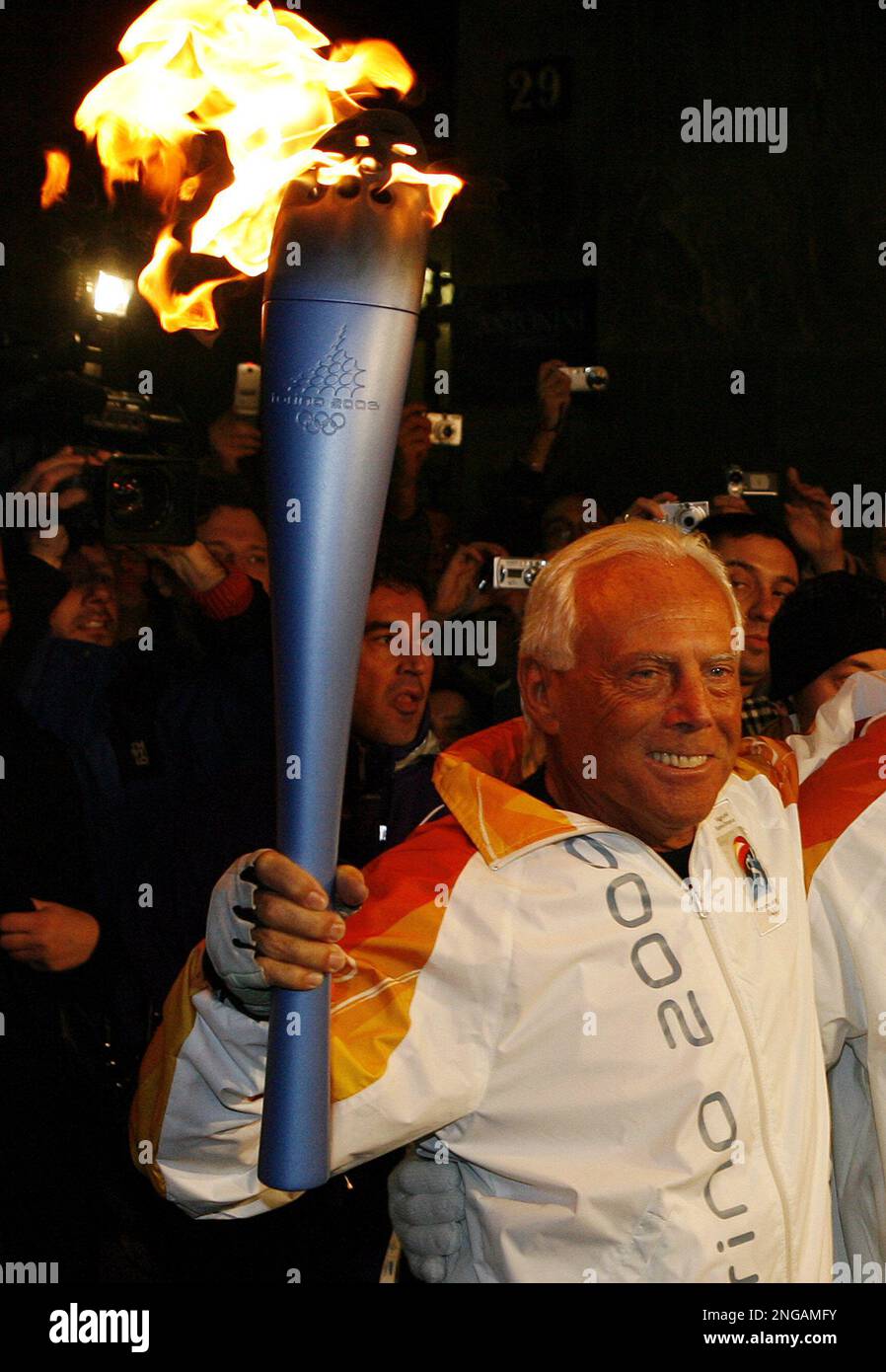 Italy's fashion designer Giorgio Armani carries the torch in Milan, as the  Olympic flame reached this northern Italy town Sunday, Jan. 29, 2006. The  flame is planned to cover 11,300 kilometers (7,022
