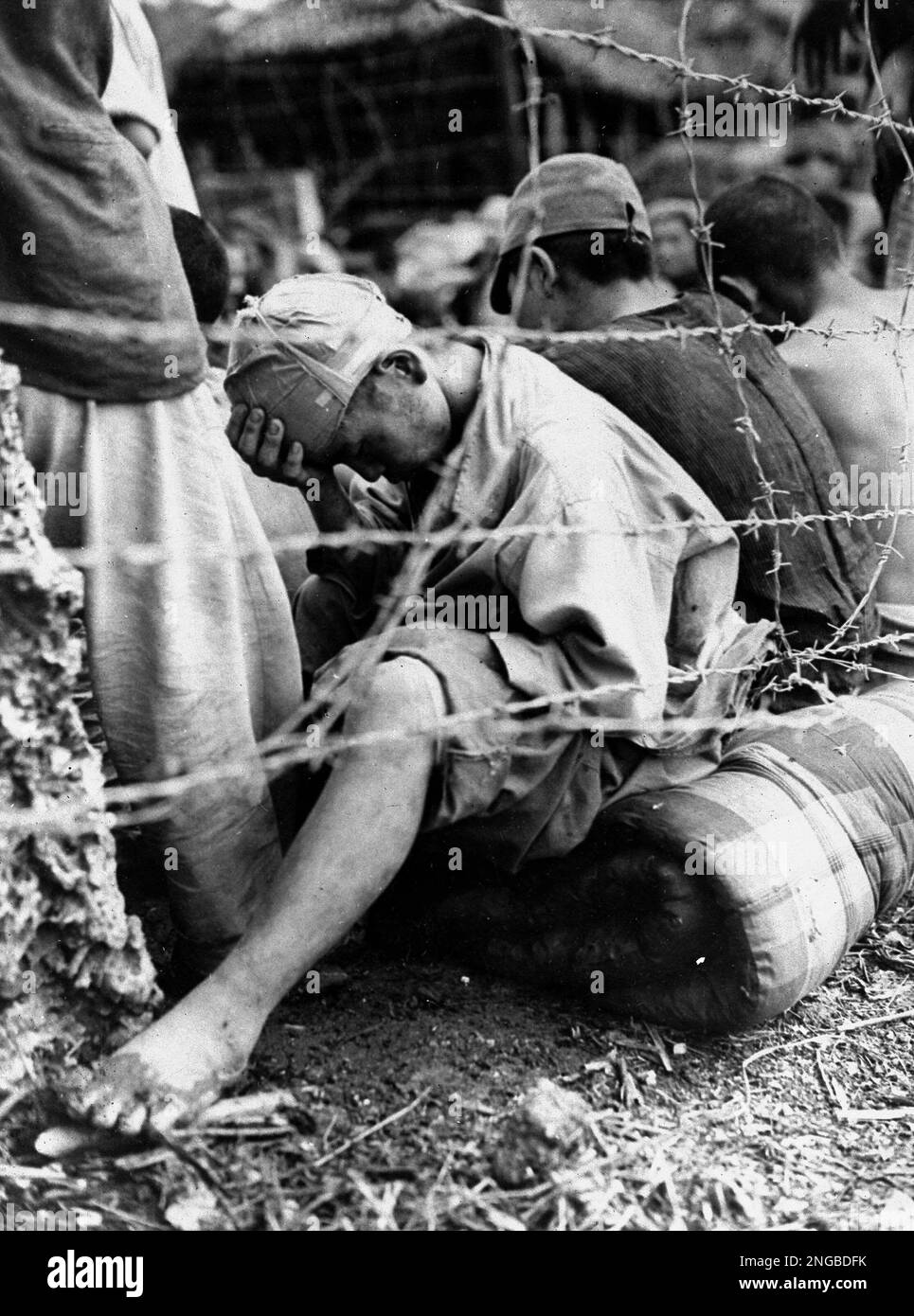A Japanese prisoner of war, sits with his head on his hand, among ...