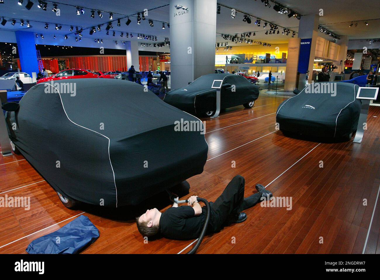 An employee uses a vacuum-cleaner under a car on the Jaguar stand at the  Paris Auto Show, Wednesday, Sept. 22, 2004. The Paris Auto Show, held every  other year, exhibits from all