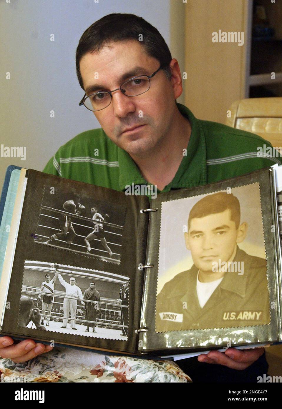 Robert Carmody Jr. holds up a photo album showing pictures of his