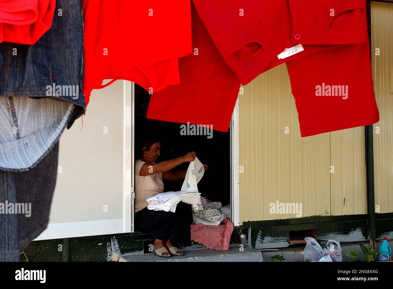 A woman sitting in the doorway of a makeshift home folds clothes at a Gypsy  camp in Spata, near Athens international airport, on Wednesday, Aug. 18,  2004. Not far from the sleek