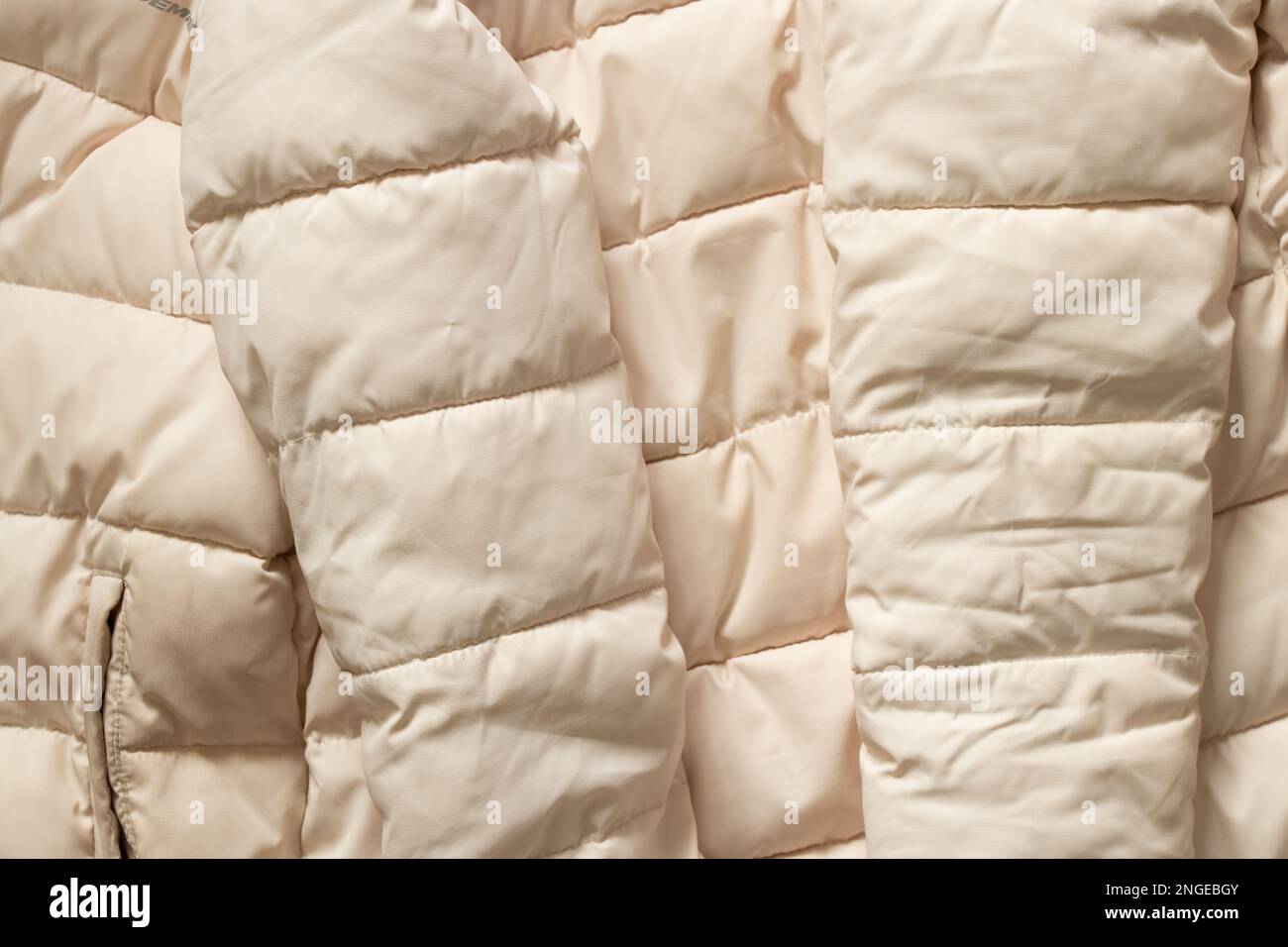 winter womens puffy white down jacket close up as background Stock Photo