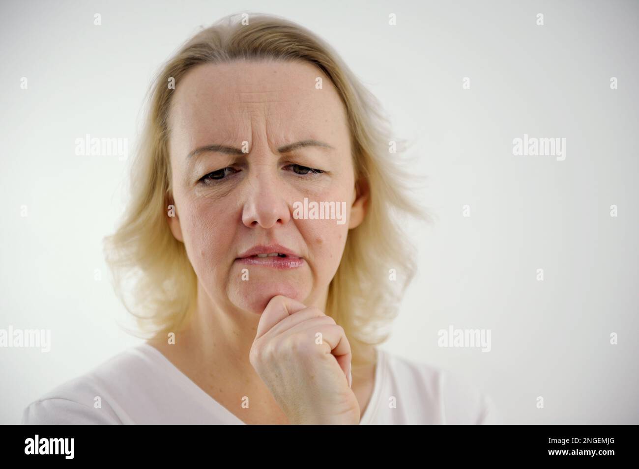 Photo of thoughtful woman bites lower lip, looks with dreamy expression