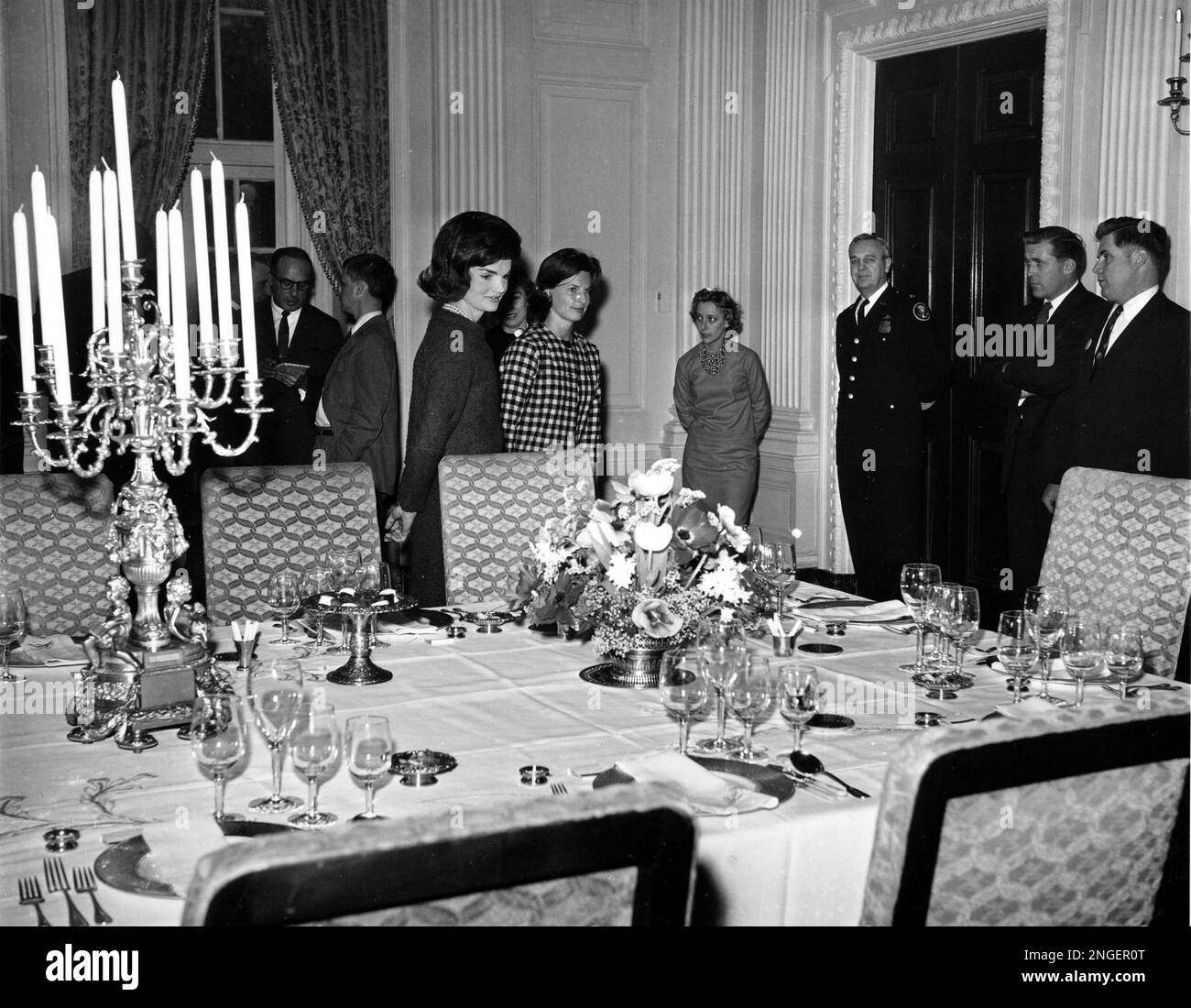 U.S. first lady Jacqueline Kennedy, center, checks the table setting of  White House gold service in the state dining room as she conducts a tour of  the White House for television cameras