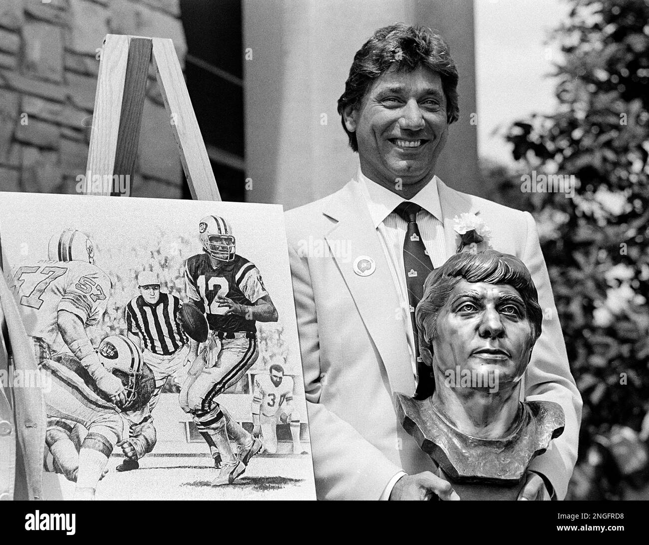 Former New York Jets quarterback Joe Namath poses with a bronze bust of