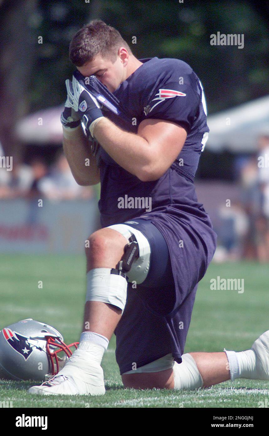 New England patriots linebacker Ted Johnson, wipes away sweat from his  forehead as he stretches during training camp Tuesday, July 30, 2002, at  Bryant College in Smithfield, R.I. Temperatures reached the upper