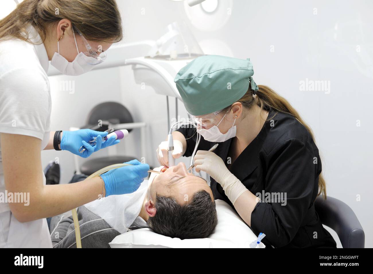 Doctor dentist with assistant helps to treat the teeth of a woman