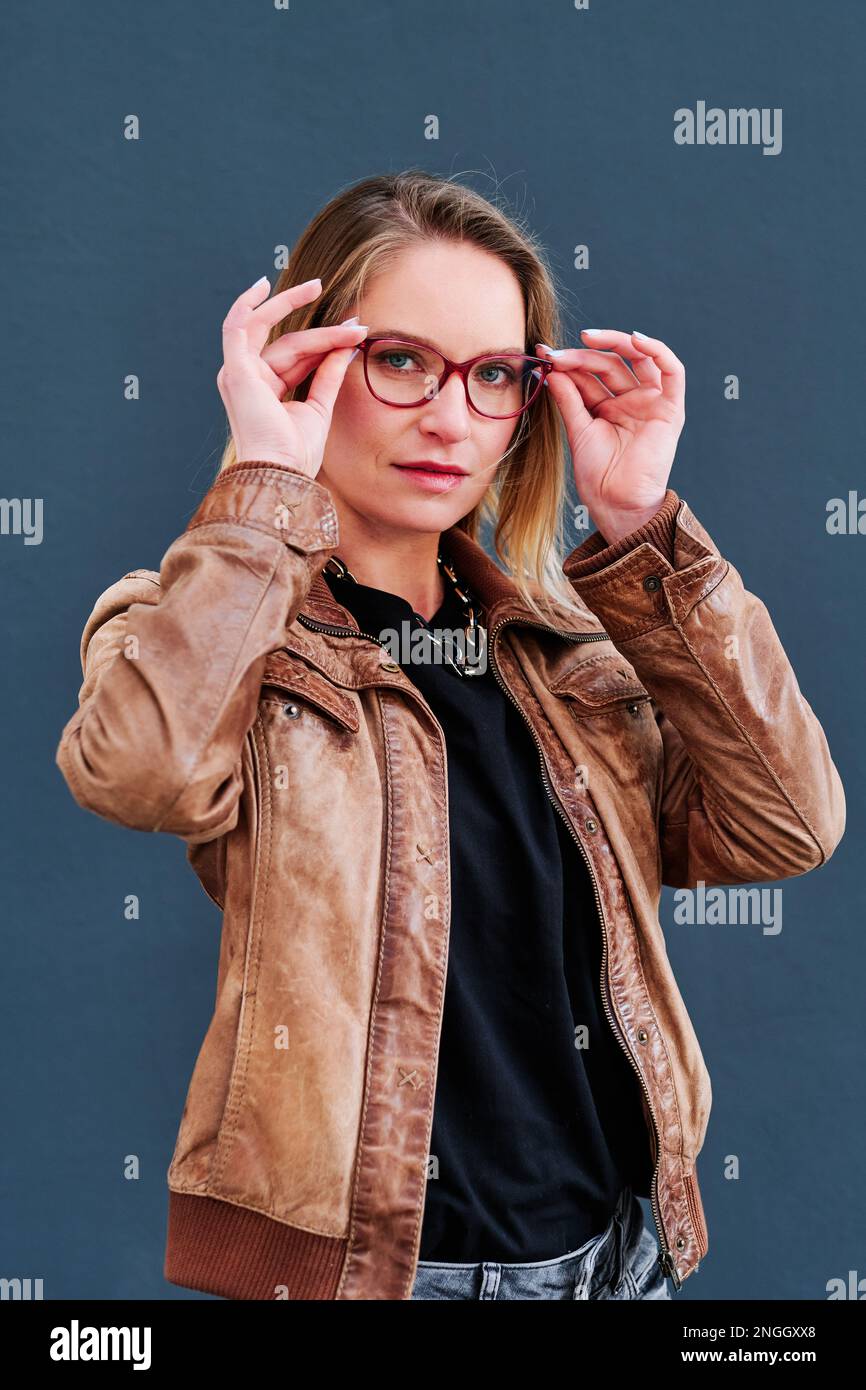 Woman with glasses looking at camera while posing against an isolated background. Stock Photo