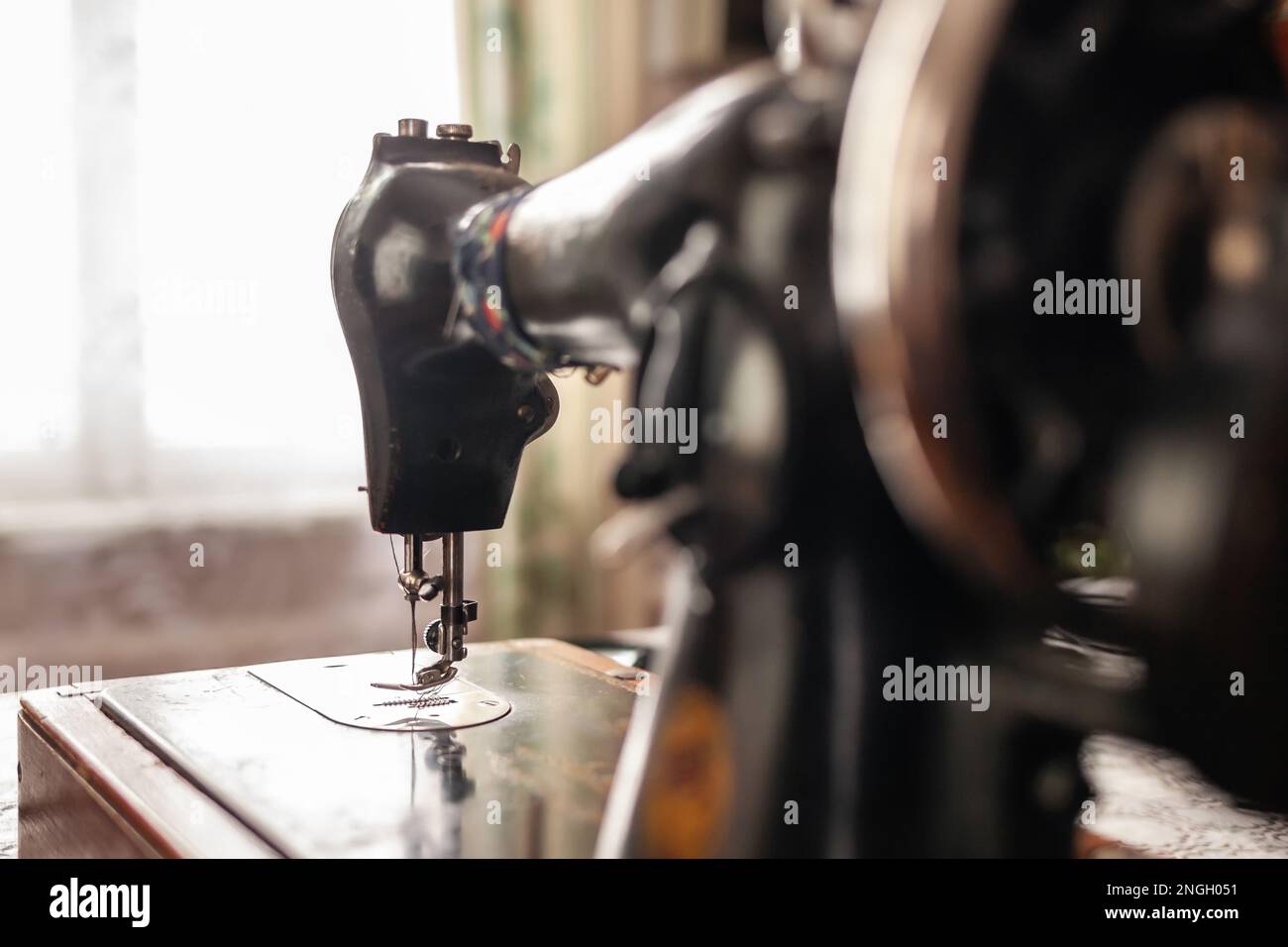 An old sewing machine stands on the table at home ready to work and sew
