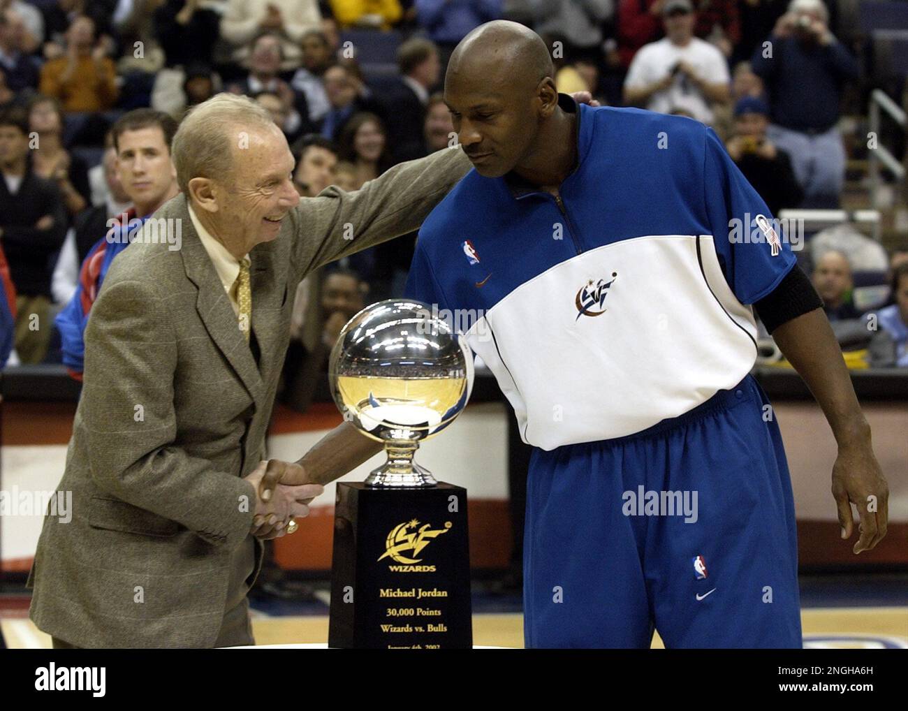 Washington Wizards' chairman of the board Abe Pollin, left, shakes hands with Wizards' Michael Jordan, right, as he presented Jordan with a trophy that commemorated his 30, 000 point scoring milestone during the halftime of their game against the Los Angeles Clippers, Tuesday, Jan. 8, 2002, at the MCI Center in Washington. The Wizards won 96-88.(AP Photo/Nick Wass) Stock Photo
