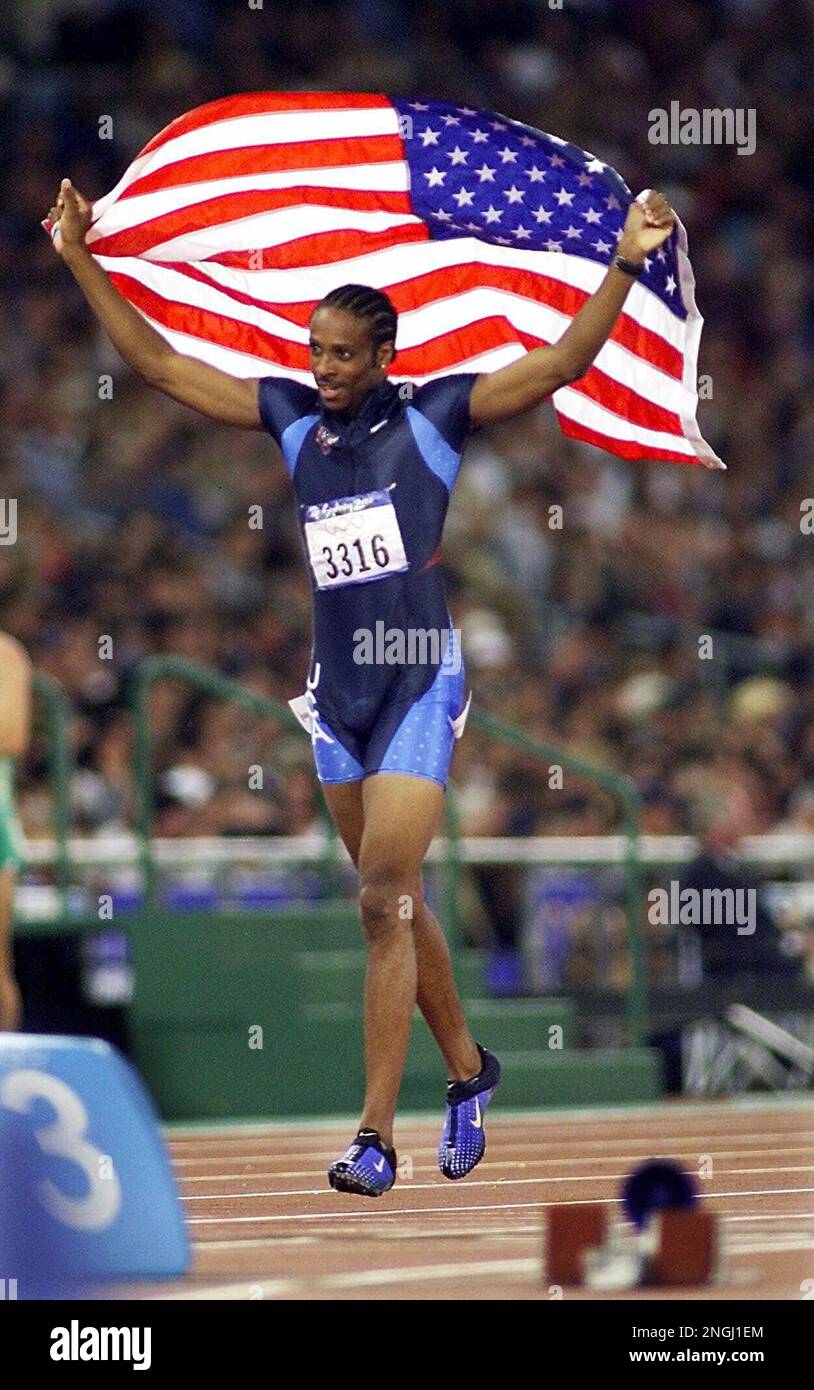 U.S. hurdler Angelo Taylor carries the U.S. flag around the track after