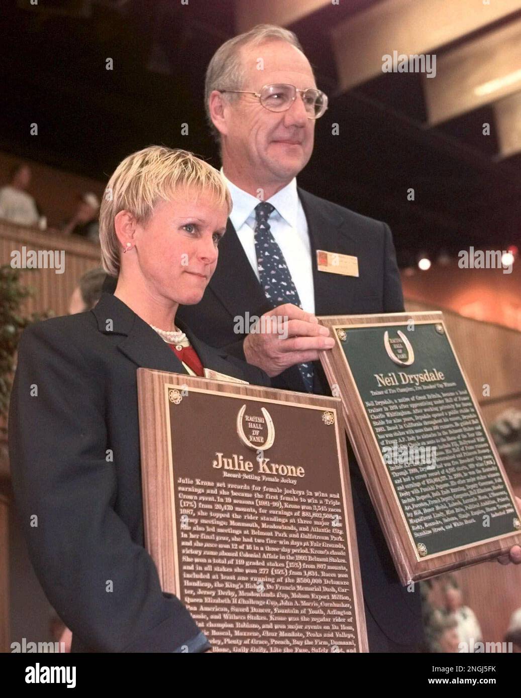 Julie Krone, the first woman jockey to be inducted into the National Racing  Hall of Fame, holds her plaque as she and Neil Drysdale, a trainer who was  inducted, pose on Monday,