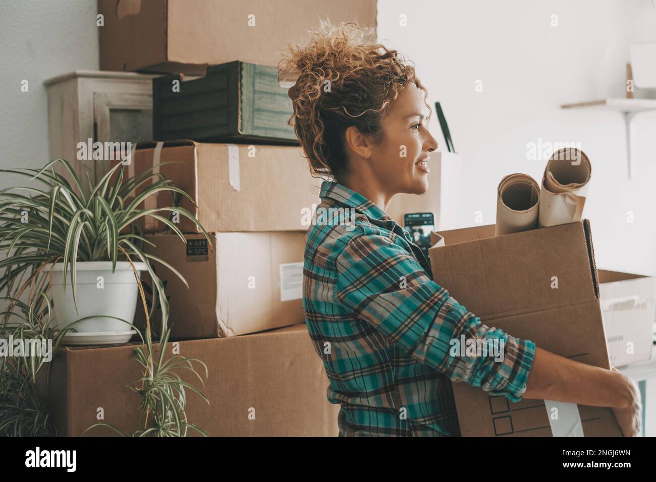Happy adult woman relocating house lifting cardboard box with life