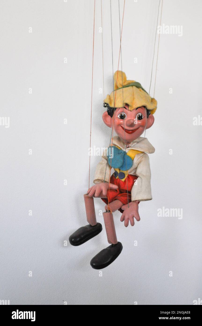 A vintage marionette puppet on a string of Pinocchio, set against a white background Stock Photo