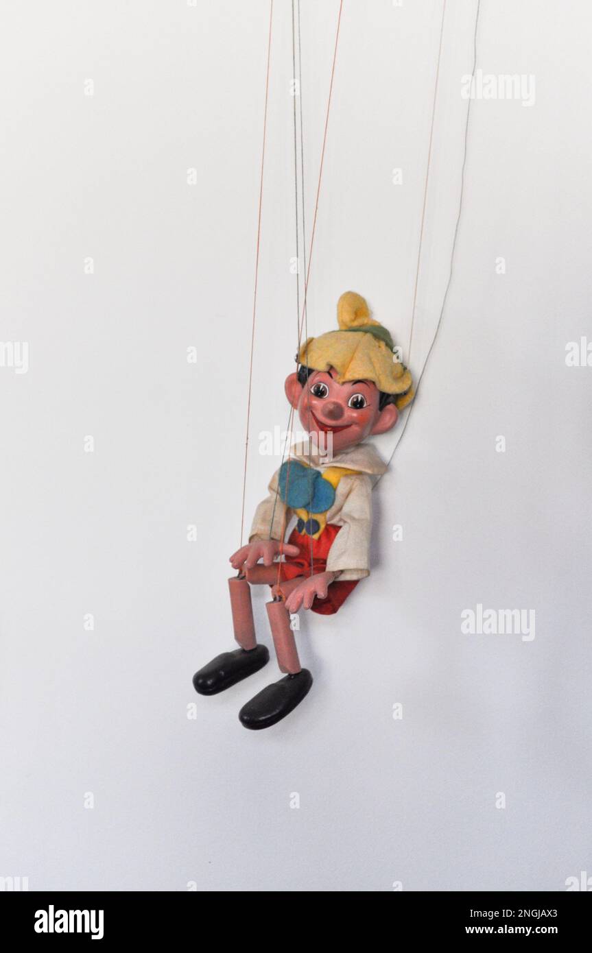 A vintage marionette puppet on a string of Pinocchio, set against a white background Stock Photo