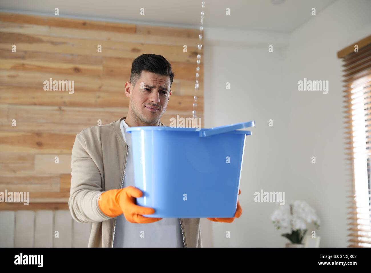 Emotional man collecting water leaking from ceiling indoors. Damaged roof Stock Photo Alamy