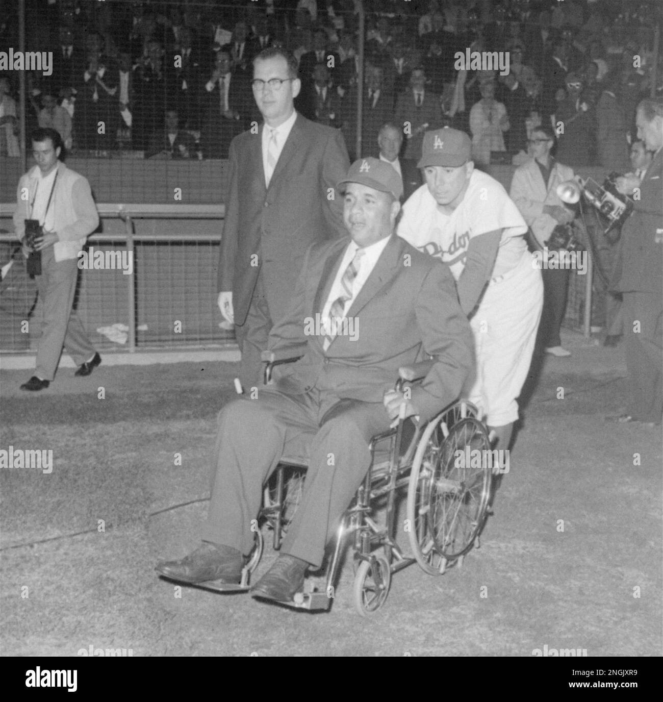 Pee Wee Reese, his old teammate, wheels Roy Campanella onto playing field  before Dodgers - Yankees exhibition in Los Angeles Coliseum May 7, 1959.  Game was in Campy's honor, and he was