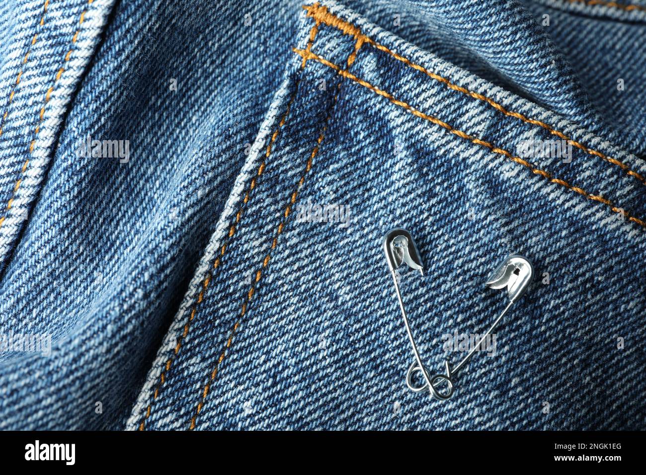 Metal safety pins on denim fabric, closeup Stock Photo Alamy