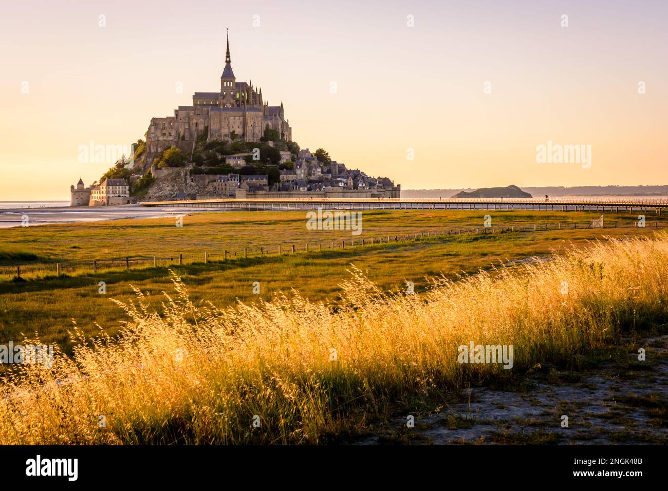 Sunset view of the Mont Saint-Michel tidal island in Normandy, France, accessible since 2014 by the new 800 meters long jetty on stilts. Stock Photo