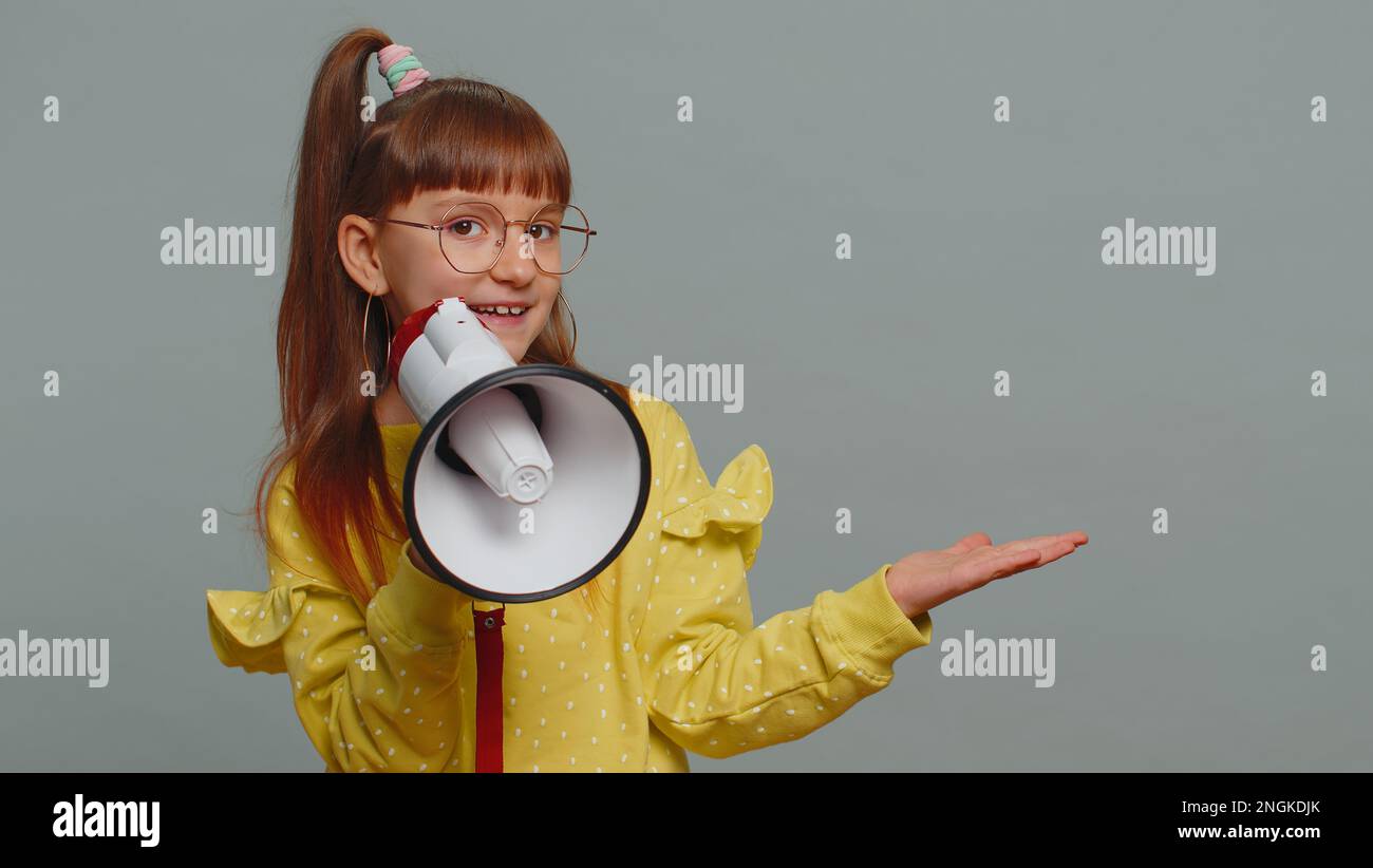 Young toddler girl in glasses scream shout in megaphone loudspeaker ...